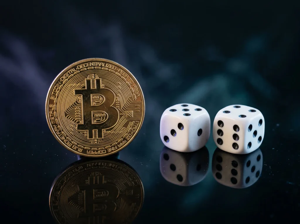 A physical Bitcoin token next to a pair of dice on a dark surface with blue and purple ambient lighting